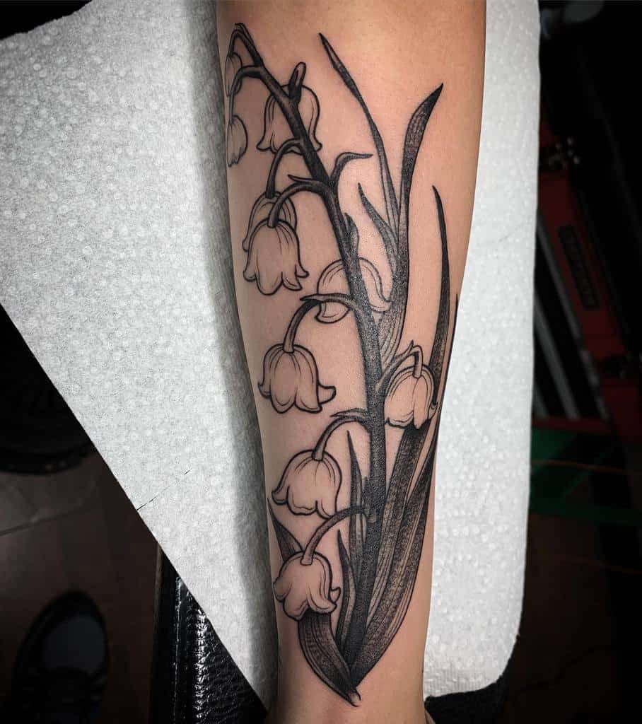 Bold black and grey Lily of the Valley tattoo, featuring strong line work, deep shading, and intricate floral details