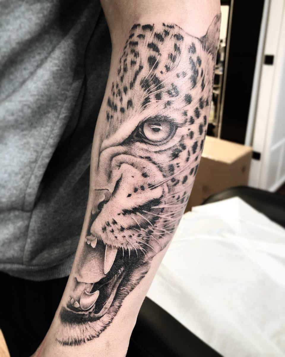 Forearm tattoo of a roaring leopard with intricate details and shading