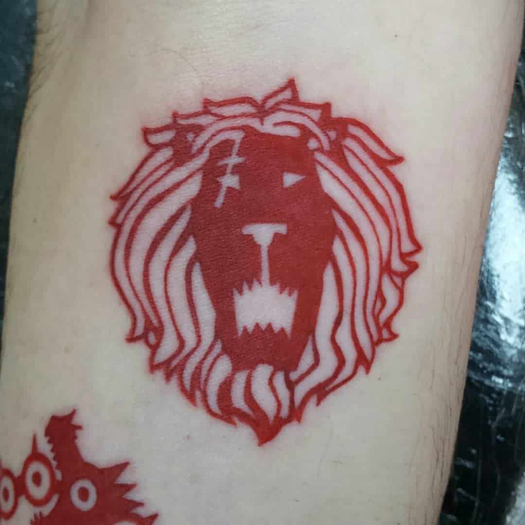 Red lion head tattoo with a scar, inked on light skin