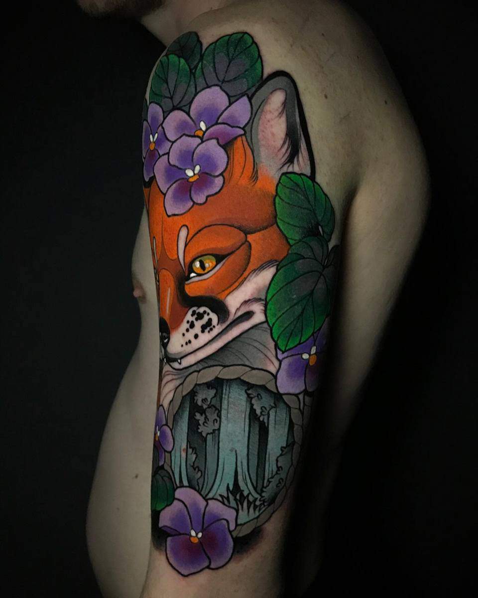 Colorful tattoo of a fox with flowers and leaves on an upper arm