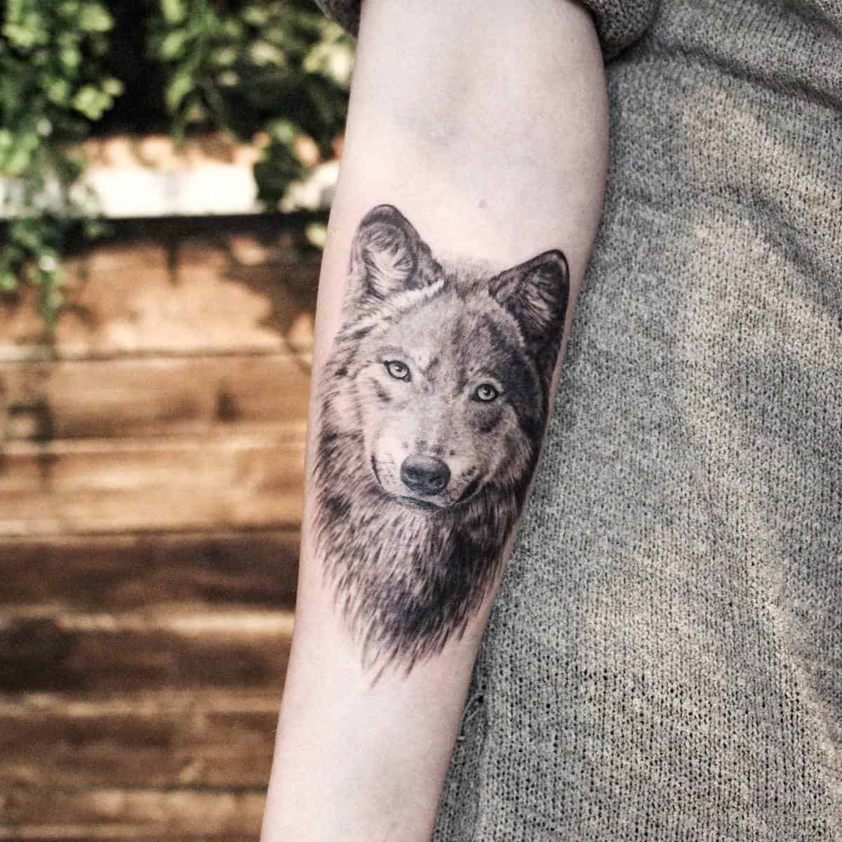 Forearm tattoo featuring a detailed wolf head