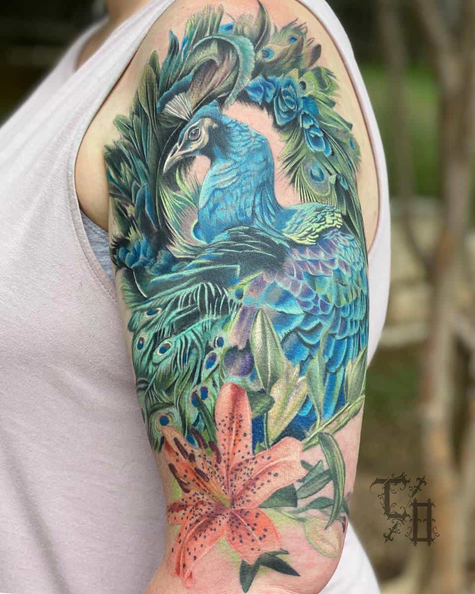 Colorful peacock and flower tattoo on an upper arm