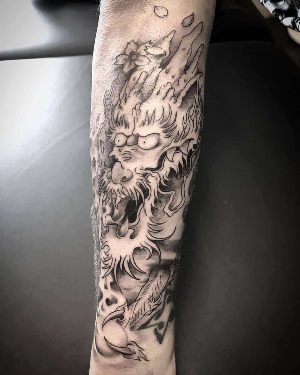 Detailed black and gray dragon tattoo on a forearm