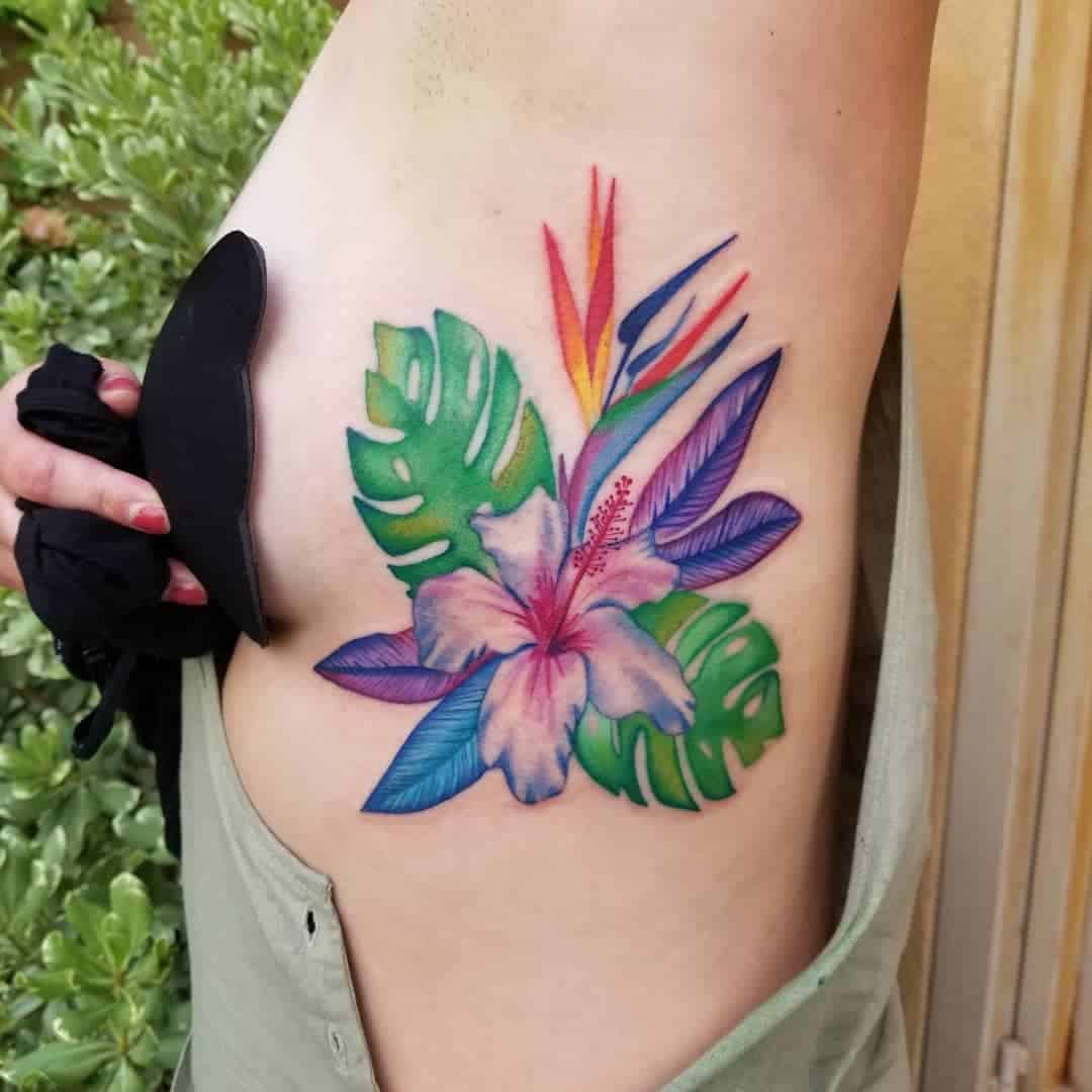 Colorful floral tattoo on a side, featuring tropical flowers and leaves