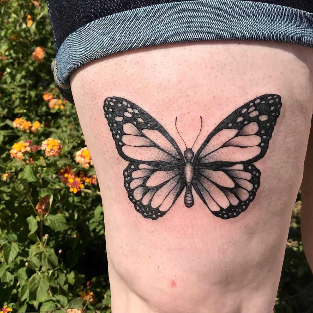 Black and white butterfly tattoo on a thigh