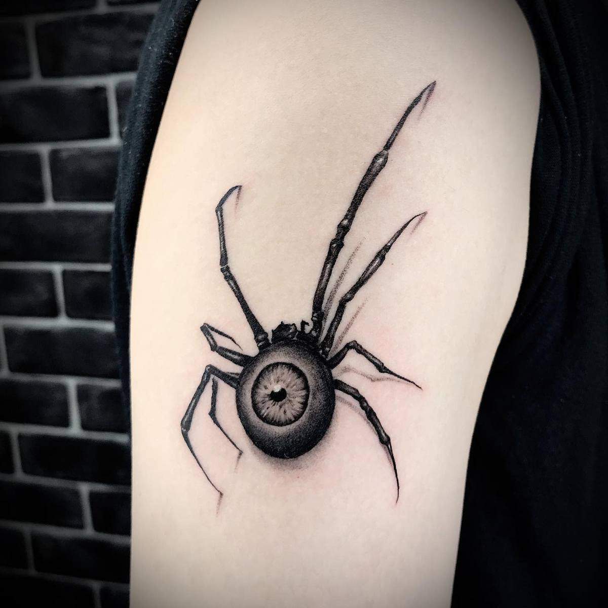 Tattoo of a spider with an eye on its body on an upper arm