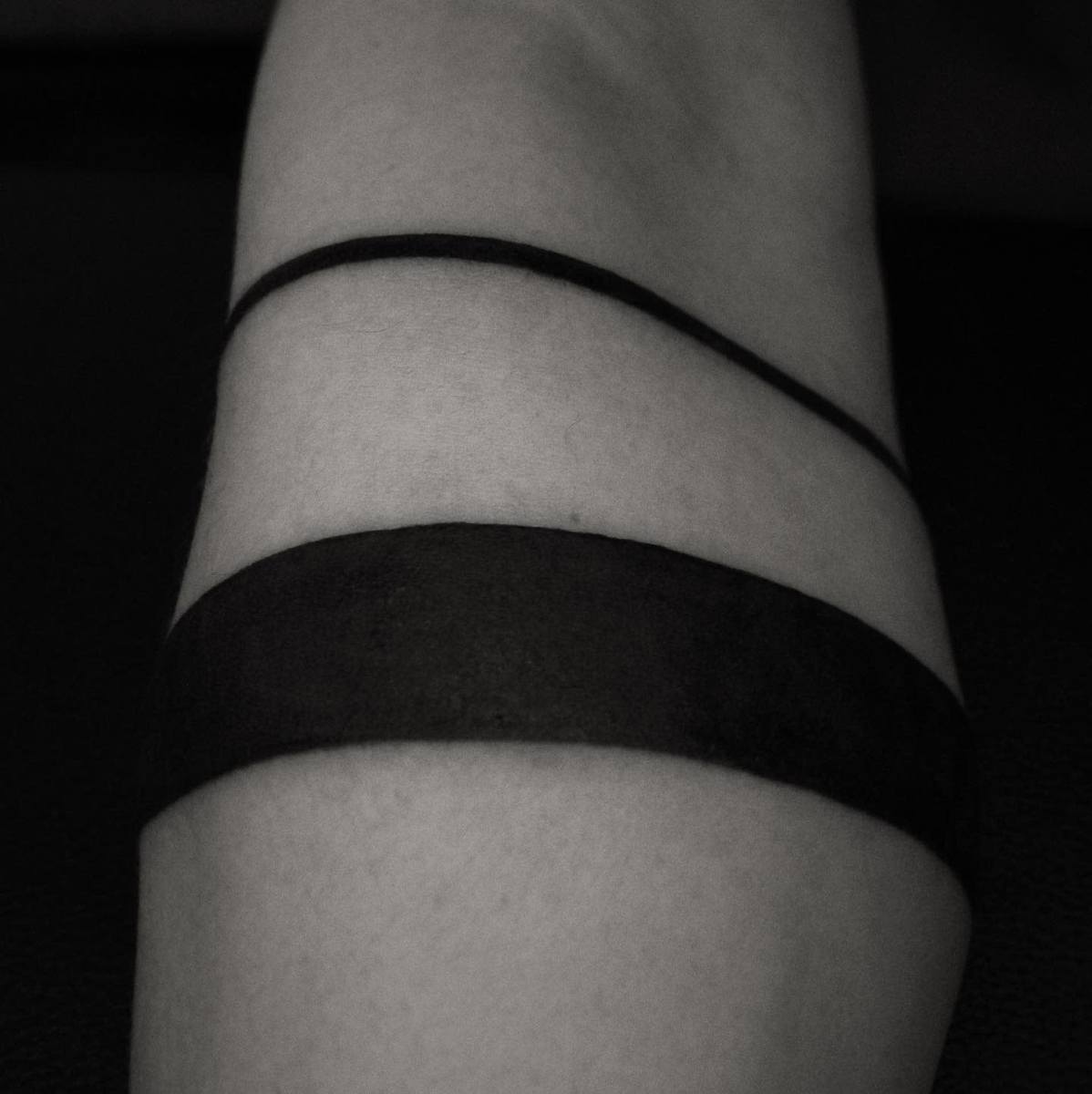 A black tattoo with two solid bands encircling an arm