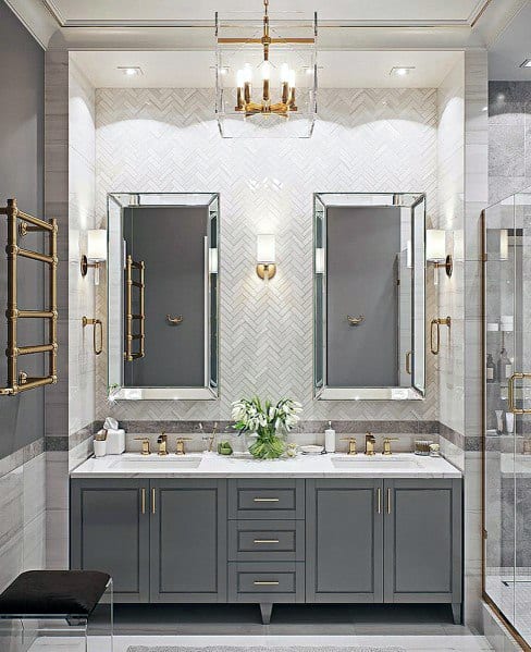 Double vanity bathroom with gold accents, dual mirrors, and elegant chandelier lighting.