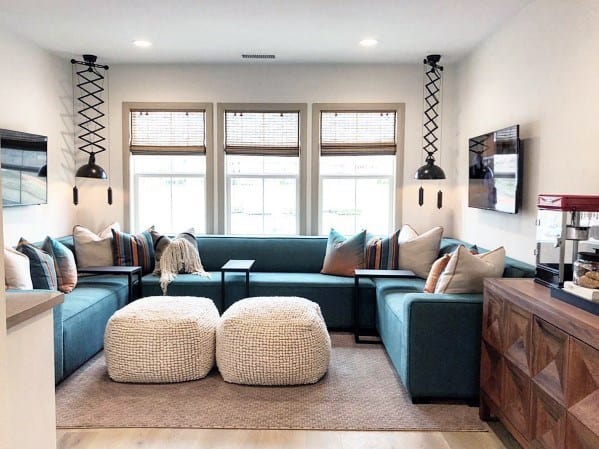 Cozy sitting area with teal sectional, pouf ottomans, and modern lighting.