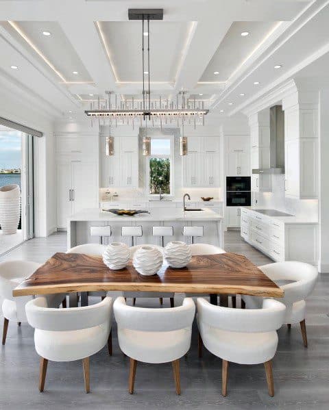 Elegant contemporary kitchen with crown molding lighting, a chic chandelier, and a stylish dining area, creating a bright and sophisticated atmosphere
