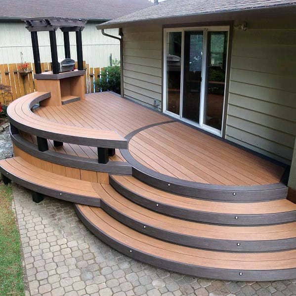 Circular wooden deck with tiered steps and a small pergola, featuring a cozy bench, adjacent to sliding glass doors