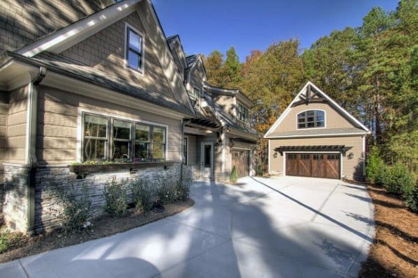 Wide concrete driveway with smooth edges leading to a rustic-style wooden garage door.