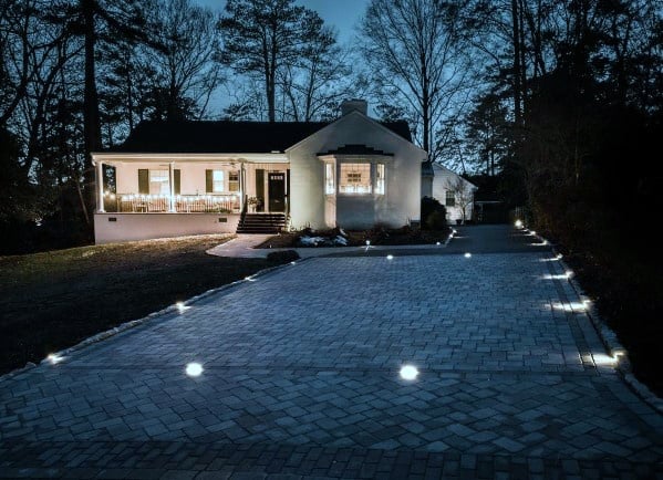 Driveway with elegant ground lighting embedded in the pavers, creating a soft and inviting ambiance leading up to the house at night