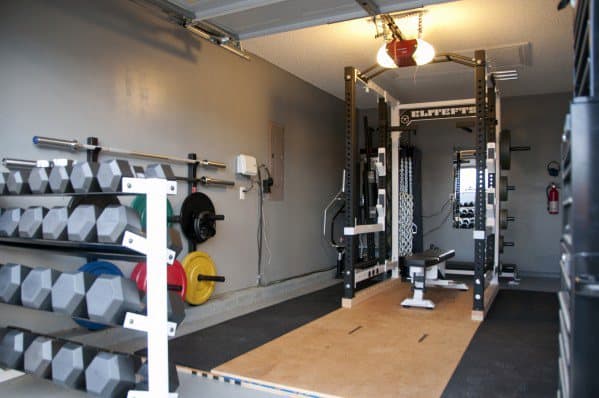 Garage gym with dumbbell rack, weight plates, power rack, and lifting platform.