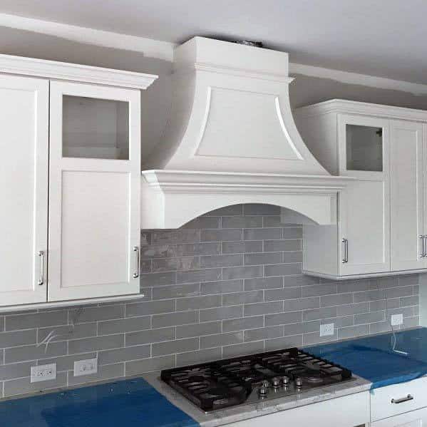 large white arched kitchen hood cover with gray tile backsplash