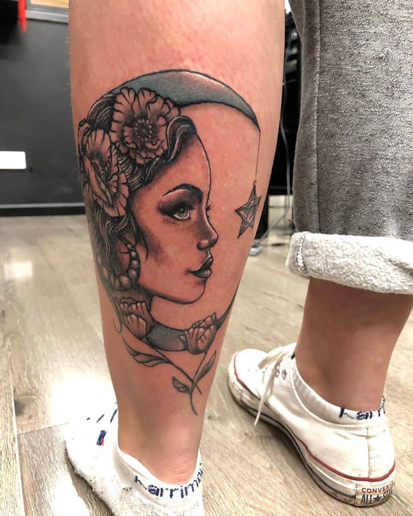 Elegant tattoo of a gypsy woman with floral hair details, a crescent moon, and a star, featuring soft shading on the calf.
