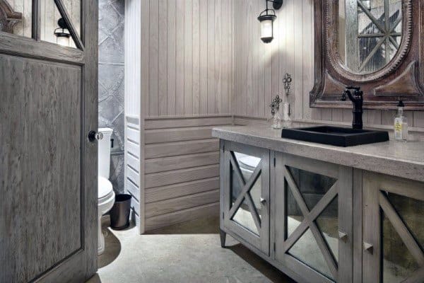Rustic bathroom with wooden cabinets, a black sink, and an ornate decorative mirror