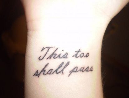 "This too shall pass" tattoo in cursive on the wrist.