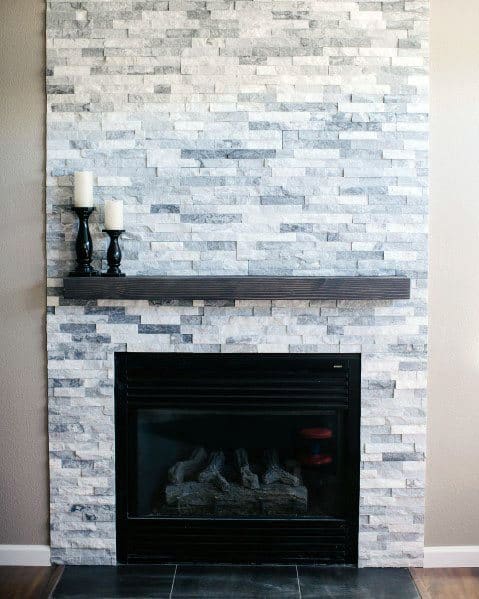 Simple stacked stone fireplace with a dark floating mantel and black gas insert for a clean, modern look