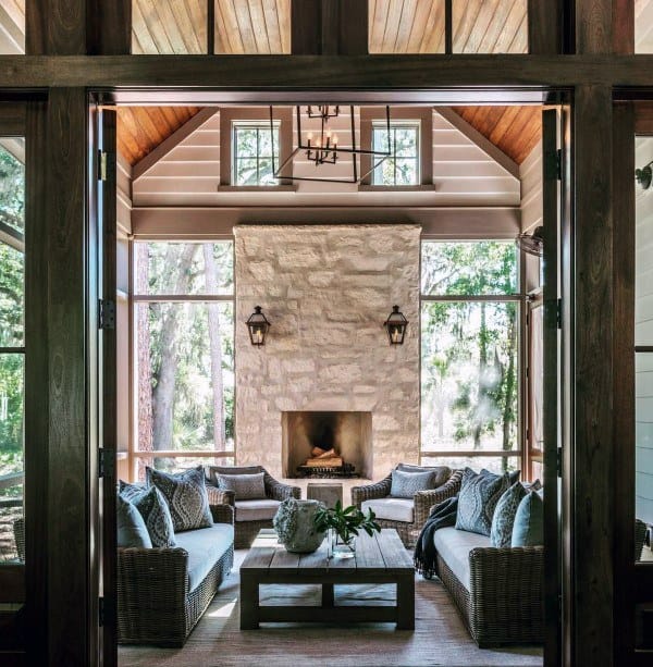 Sunroom with a white stone fireplace, wicker seating, and lantern lighting.