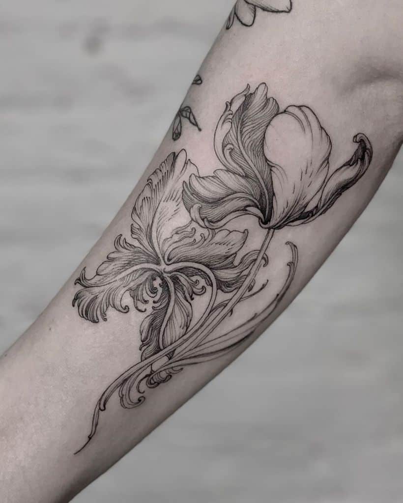 Tattoo of two delicate, shaded tulips with swirling stems on a forearm