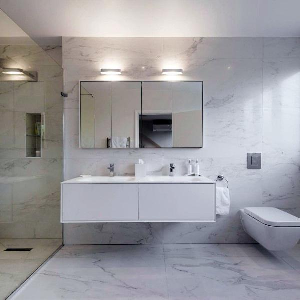 Modern bathroom with white marble walls, mirror cabinets, floating sink, and glass shower enclosure