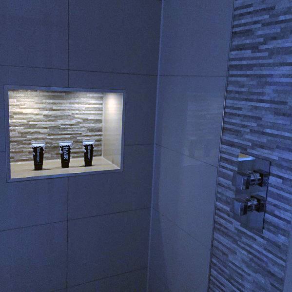Stylish shower with LED-lit niche shelf showcasing products, surrounded by sleek tile work for a modern, organized design