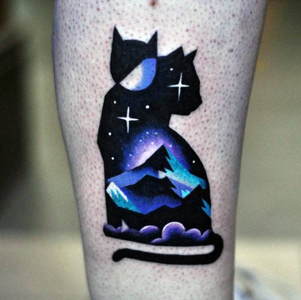 Vibrant cosmic cat tattoo featuring a starry night sky and mountain landscape within its silhouette, creating a dreamy and artistic design.