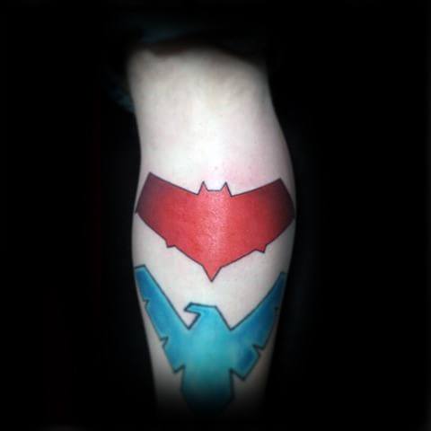 Minimalist calf tattoo featuring red Red Hood and blue Nightwing emblems stacked vertically for a bold, clean superhero tribute.
