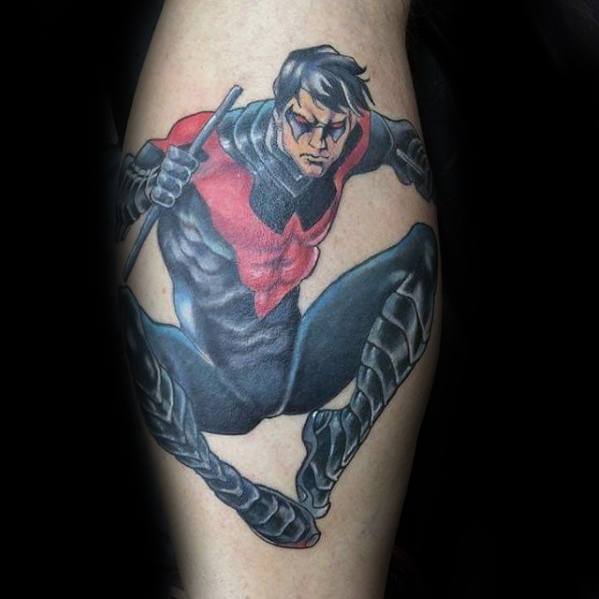 Dynamic Nightwing tattoo in his red and black suit, captured mid-leap with escrima sticks and bold comic-style detailing.