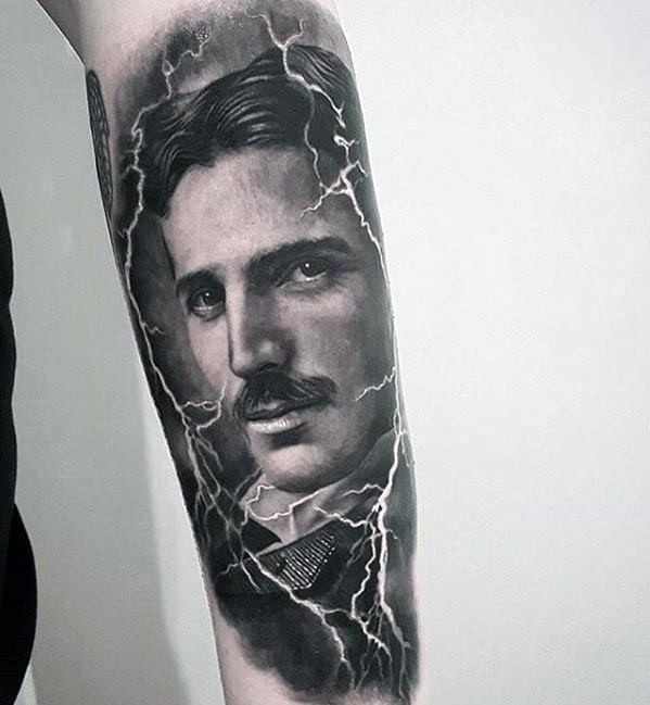 Hyper-realistic black and grey Nikola Tesla tattoo with intense gaze, surrounded by dramatic lightning bolts and soft background shading.