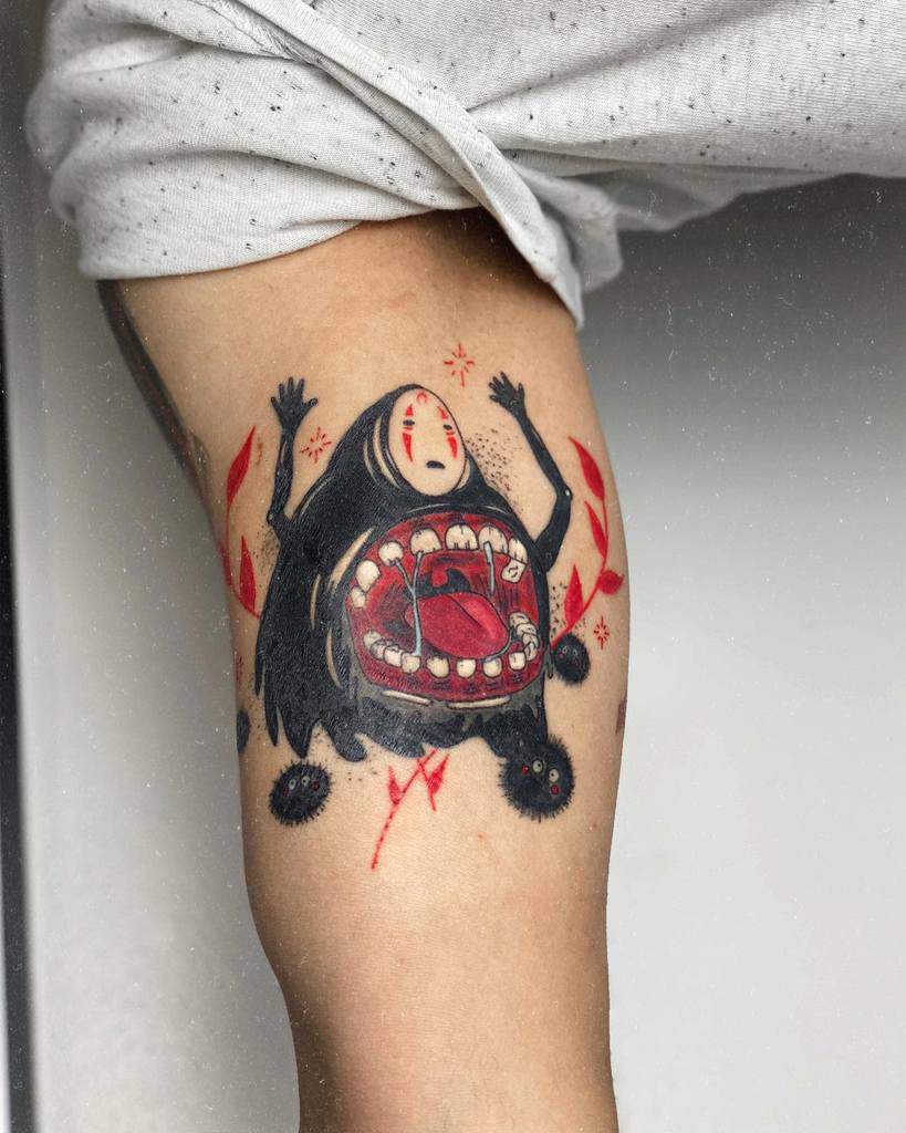 Bold black and red tattoo of No-Face from Spirited Away in monstrous form, with an open mouth, soot sprites, and dynamic red accents