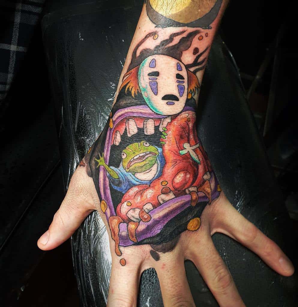 Bold and colorful Spirited Away tattoo of No-Face in monstrous form, devouring Aogaeru, with dramatic details and shading