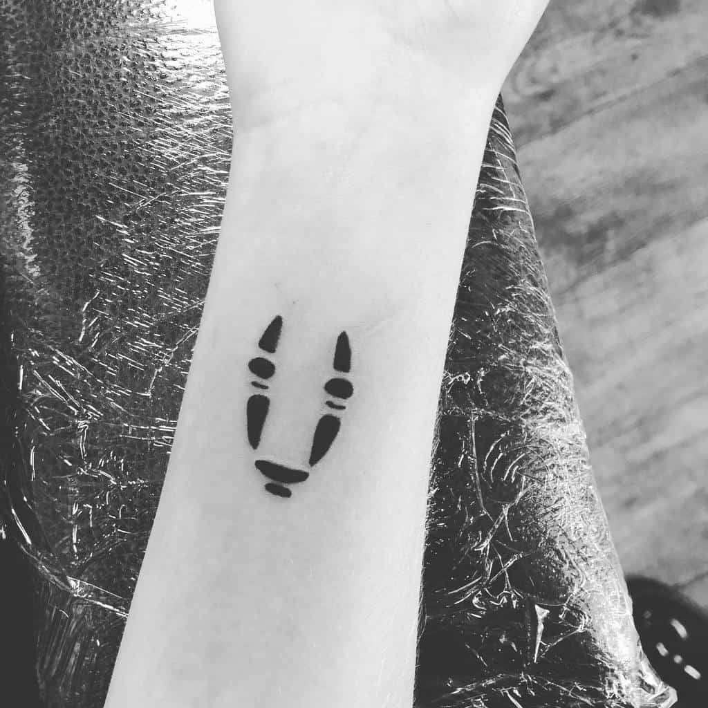 Minimalist black ink tattoo of No-Face’s facial markings from Spirited Away, in a simple and subtle design