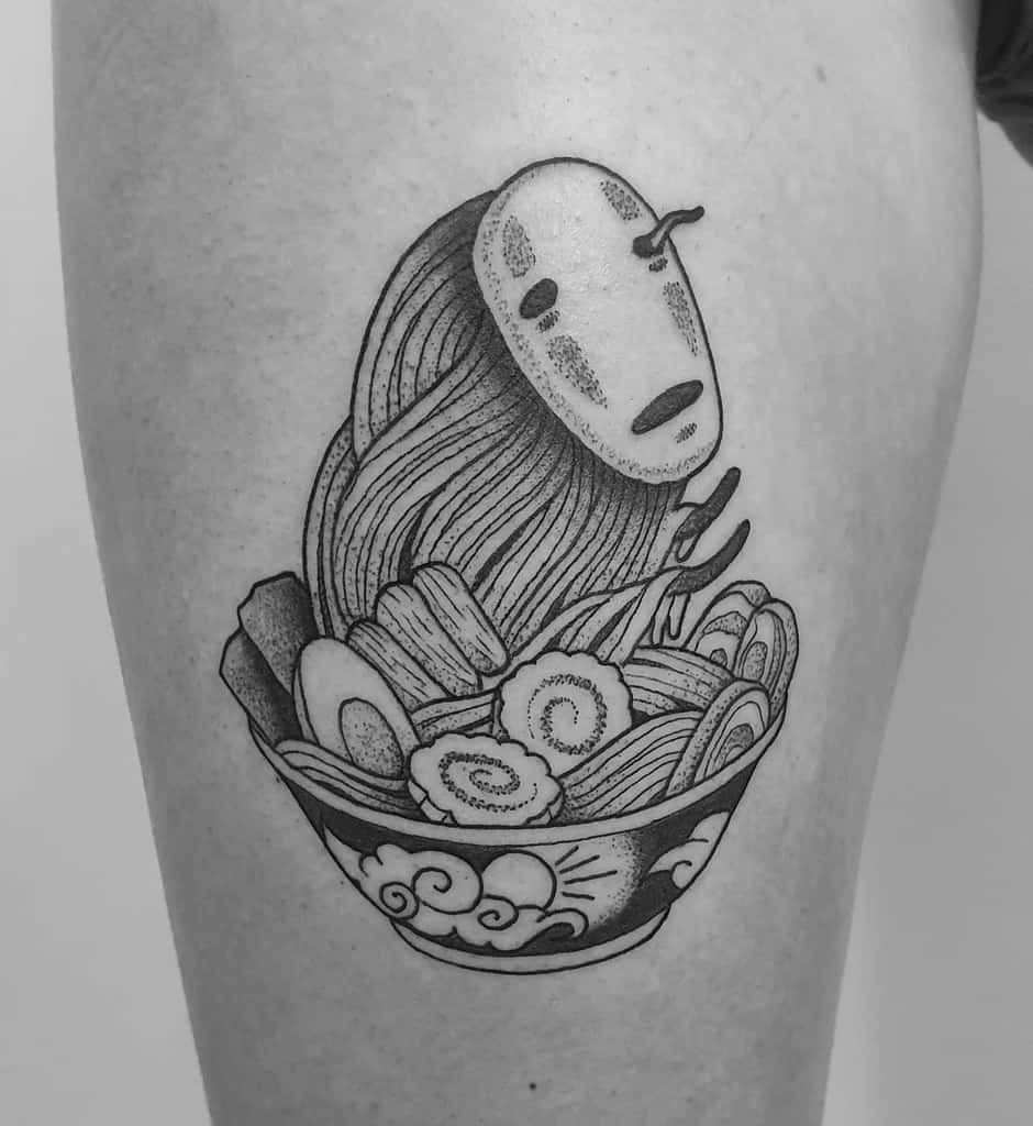 Black and grey tattoo of No-Face from Spirited Away emerging from a ramen bowl, with intricate linework and detailed food elements