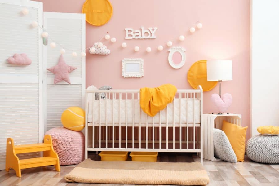 Pink nursery with white crib, wall divider, and yellow accent decor.