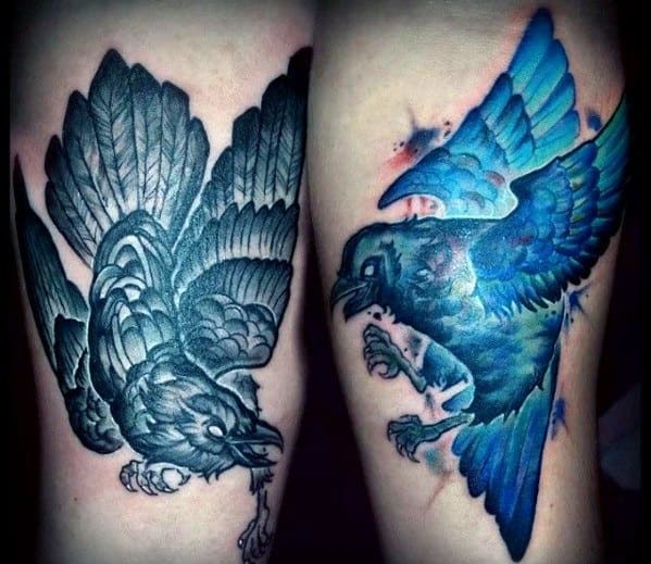 Vibrant tattoo of Huginn in black and Muninn in electric blue, each in mid-flight with fierce expressions and bold contrast on the legs.
