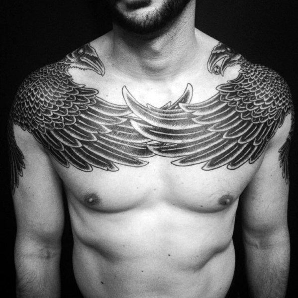 Symmetrical chest tattoo of Huginn and Muninn with wings spread wide across the shoulders, featuring bold linework and feather detail.