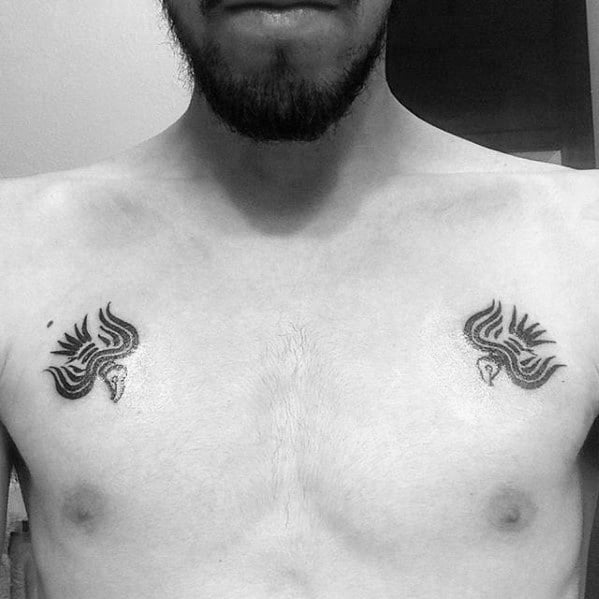 Minimalist chest tattoos of Huginn and Muninn in symmetrical, tribal-style design, placed above each pectoral in bold black ink.