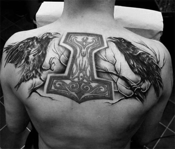 Back tattoo featuring Huginn and Muninn perched on branches with a large, detailed Mjölnir centered between them, symbolizing Odin’s presence.