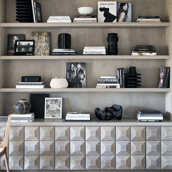 Modern bookshelf with decorative objects, books, and abstract art on wooden shelves and patterned cabinet below