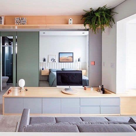 Compact studio with multifunctional desk, cozy bed, and vibrant greenery accents.