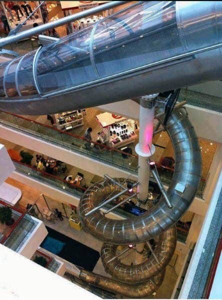 A spiral slide winds through the multi-level mall under a transparent canopy