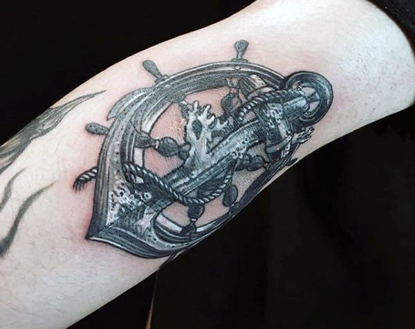 Tattoo of an anchor intertwined with a ship's wheel and rope on an arm
