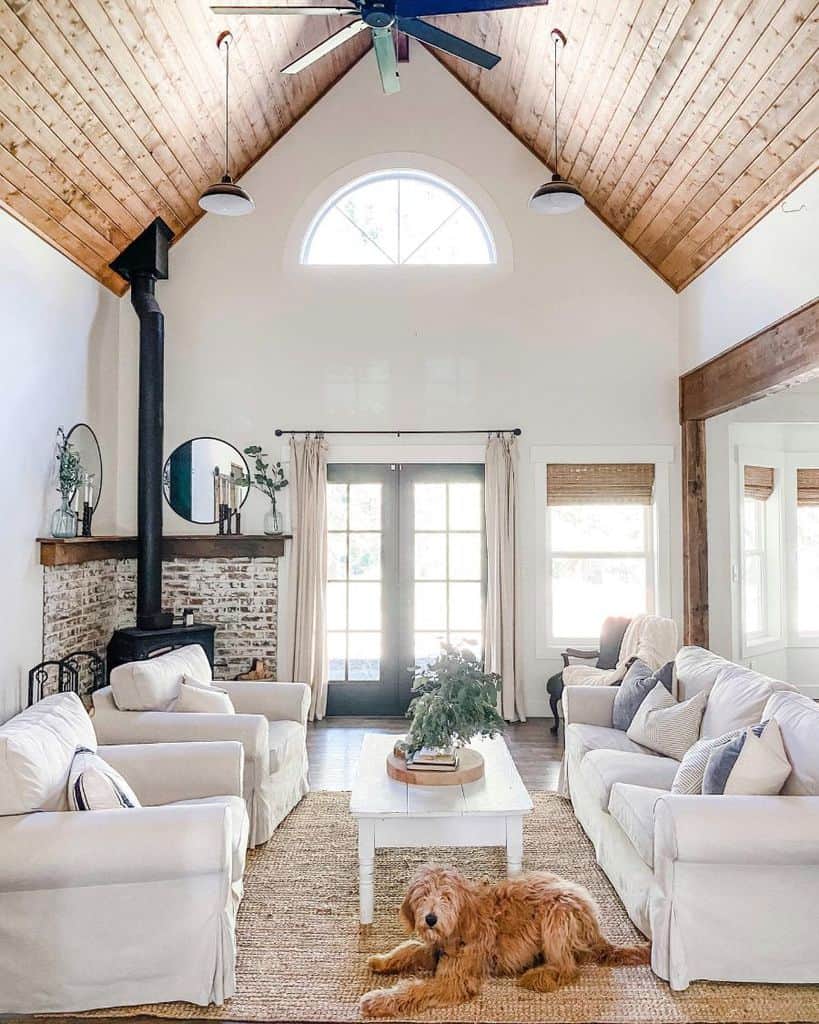 high wood ceiling modern farmhouse living room brick wall fireplace white sofas white wood living room table