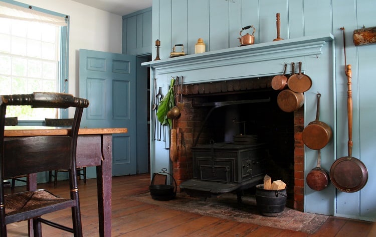 blue fireplace with hanging copper pots in rustic kitchen