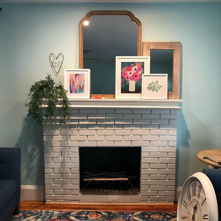 gray brick fireplace with framed artwork on the mantel