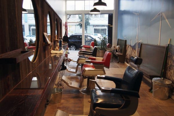 Retro-style barbershop with vintage chairs, large windows, and rustic wooden decor.