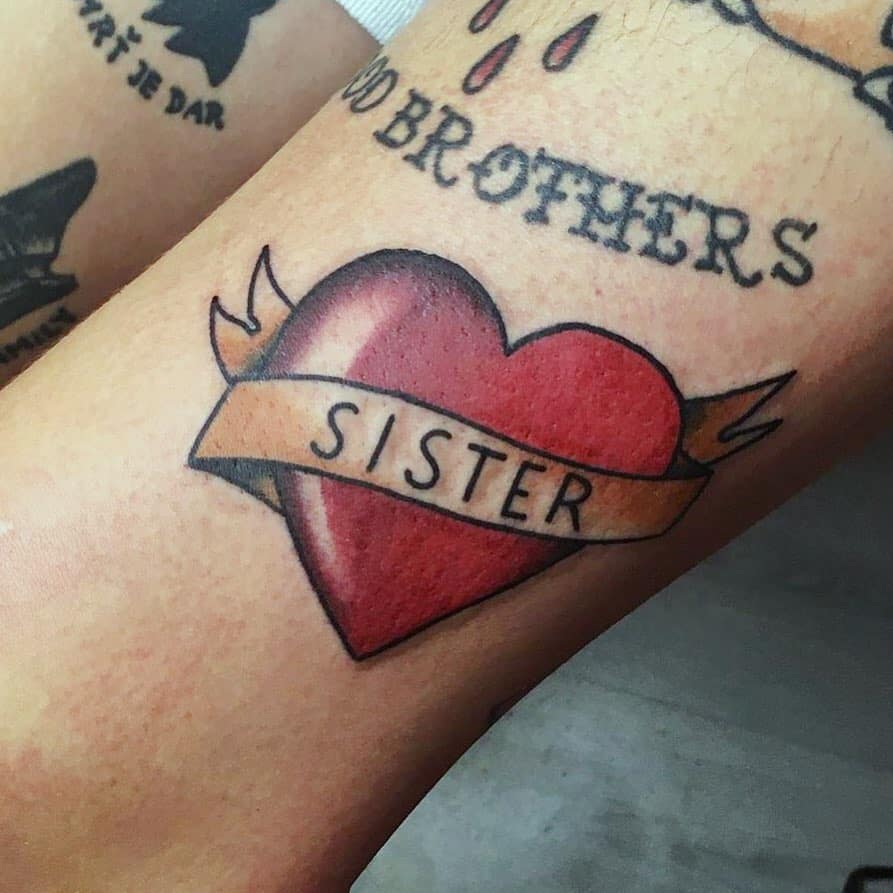 Traditional-style tattoo of a red heart with a banner reading 'Sister,' symbolizing love and a strong sibling bond