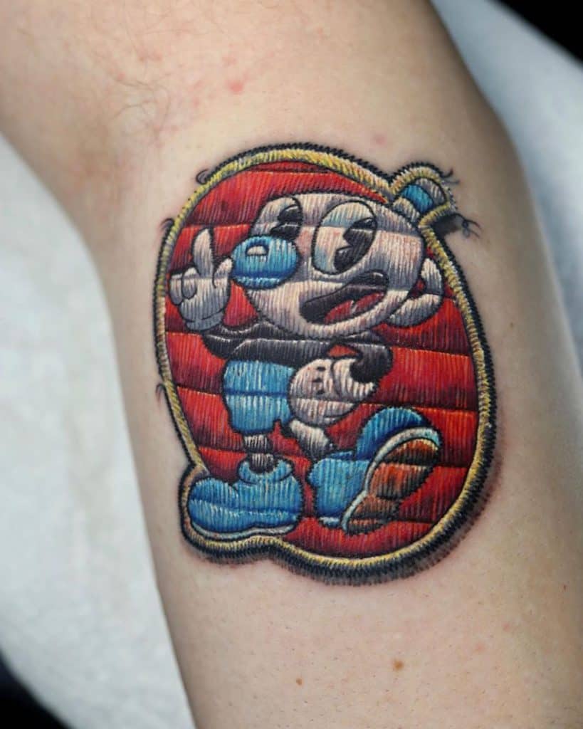 Stylized embroidered tattoo of a classic cartoon figure with bold stitch details and a colorful, handcrafted textile look.